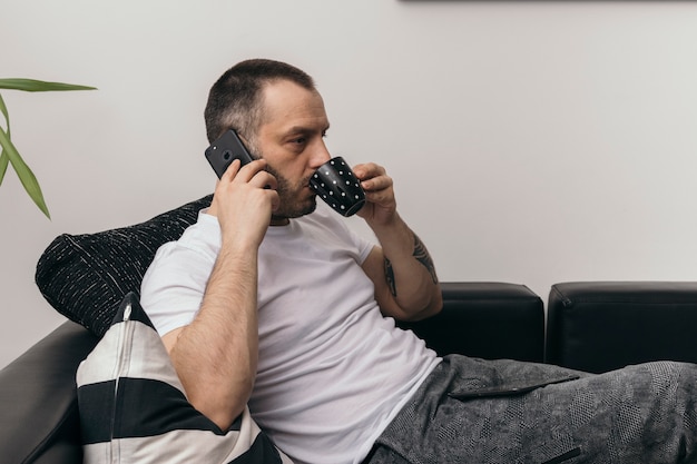 Mann, der am Telefon trinkt und spricht