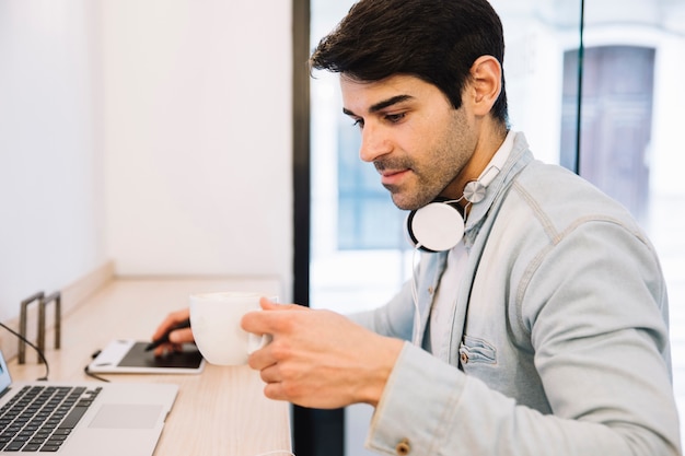 Kostenloses Foto mann, der an dem computer hält schale arbeitet