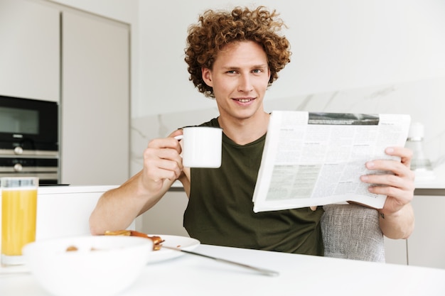 Mann, der an der Küche sitzt, während Zeitung hält