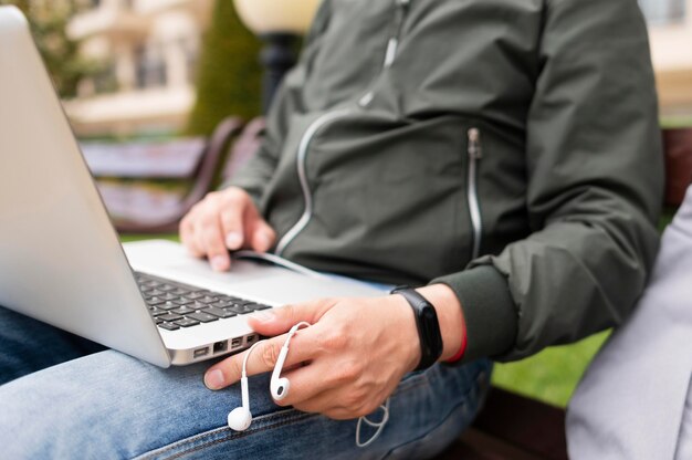 Mann, der an Laptop außerhalb mit Kopfhörern arbeitet