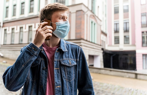 Mann, der an seinem Telefon spricht, während er eine medizinische Maske trägt