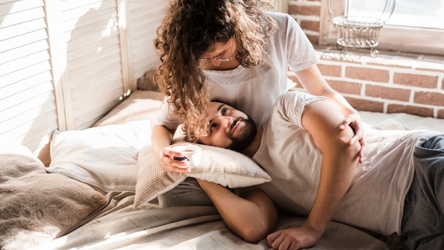 Mann, der auf dem Schoss der Frau sitzt, der über Bett sitzt