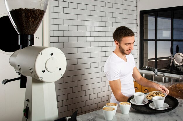 Mann, der auf den Behälter Tasse Kaffees und Plätzchen setzt