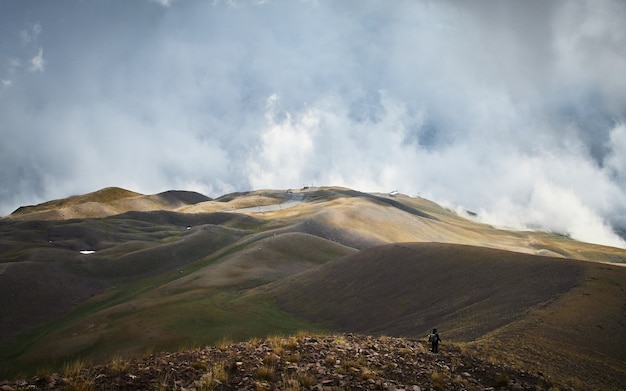 Kostenloses Foto mann, der auf einem berg mit einem bewölkten himmel geht