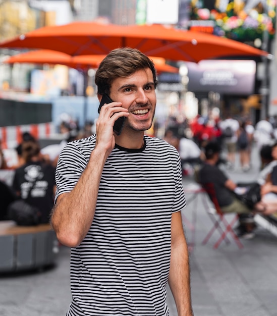 Mann, der auf einem Smartphone vor einer Terrasse spricht