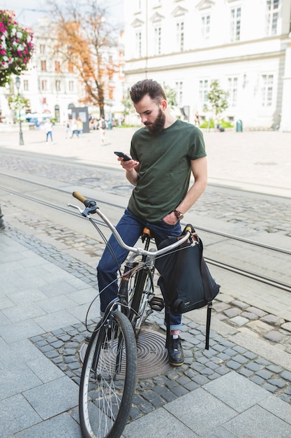 Kostenloses Foto mann, der auf fahrrad unter verwendung des handys sitzt