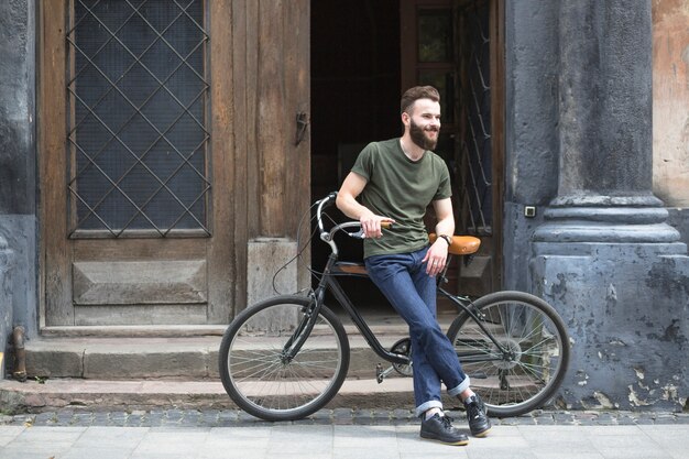 Mann, der auf Fahrrad vor einer offenen Tür sitzt