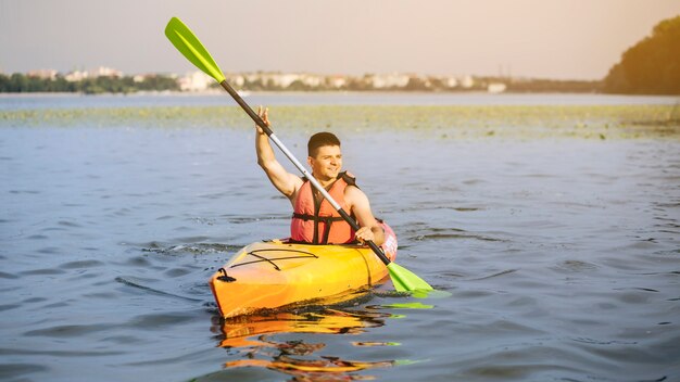 Mann, der auf idyllischem See unter Verwendung des Paddelns kayaking ist