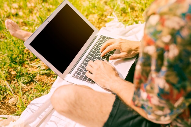 Mann, der auf Laptop in der Lichtung surft
