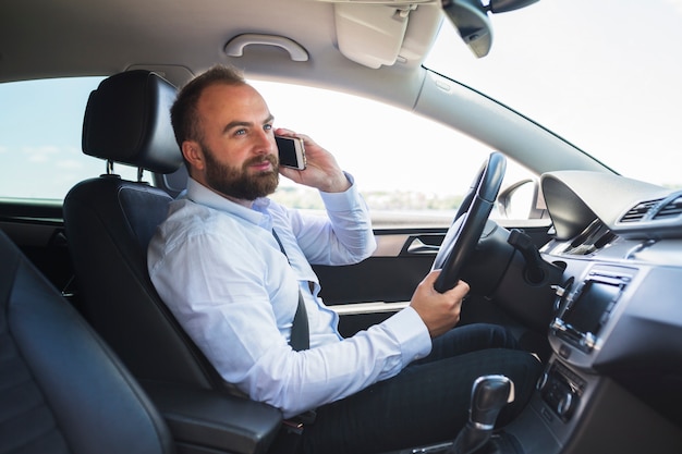 Mann, der auf Smartphone beim Fahren des Autos spricht