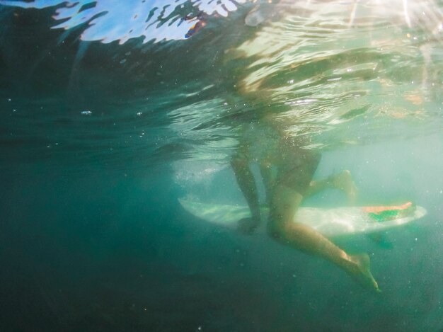 Mann, der auf Surfbrett im blauen Meer sitzt