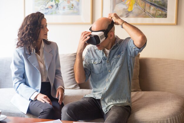 Mann, der auf VR-Kopfhörer für aufpassende Darstellung sich setzt