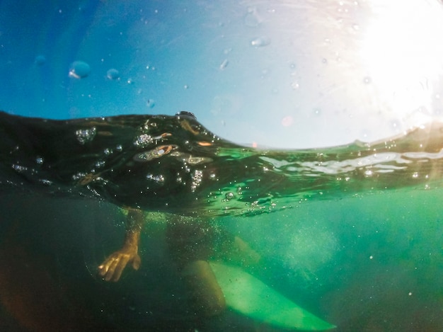 Mann, der auf weißem Surfbrett im Meer sitzt