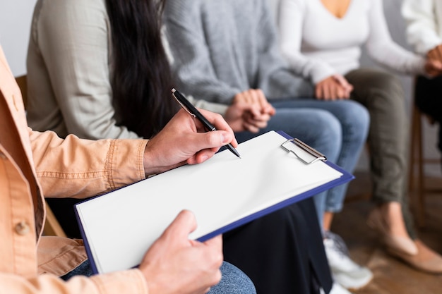 Mann, der auf Zwischenablage bei einer Gruppentherapiesitzung schreibt