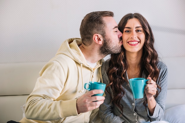 Kostenloses Foto mann, der backe der frau mit cup küsst