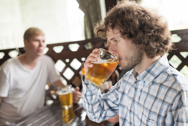 Kostenloses Foto mann, der bier nahe freunden in der kneipe genießt