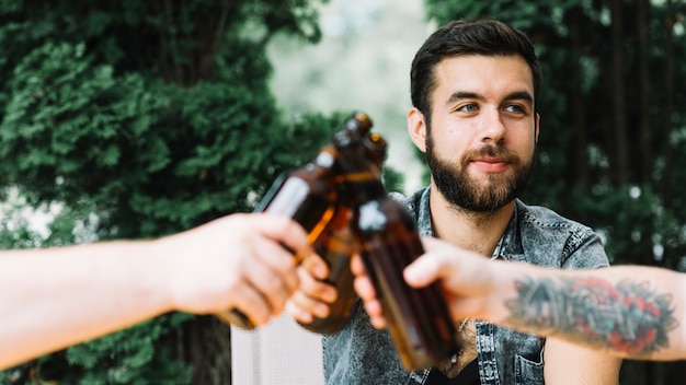 Mann, der Bierflaschen mit seinen Freunden klirrt