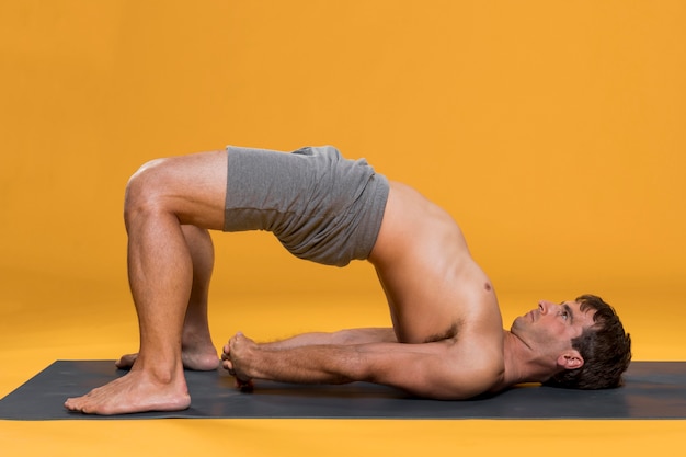 Mann, der Brückenhaltung auf Yogamatte tut