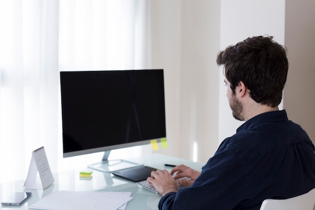 Kostenloses Foto mann, der computer im büro durchstöbert