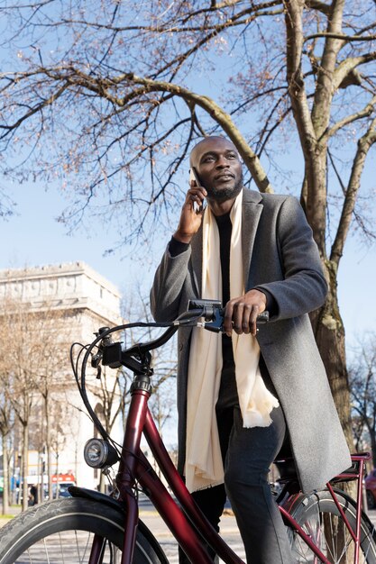 Mann, der das fahrrad fährt und auf dem smartphone in der stadt in frankreich spricht