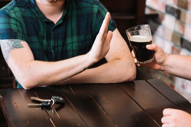 Mann, der das Glas Rum verweigert, das von seinem Freund angeboten wird