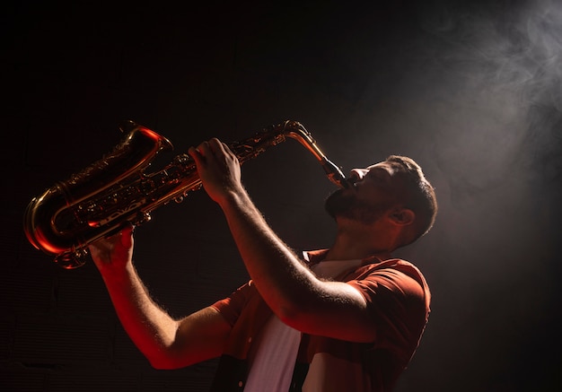 Mann, der das Saxophon im Scheinwerferlicht spielt