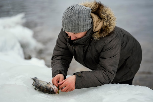 Mann, der den Fisch vom Köder der Rute befreit