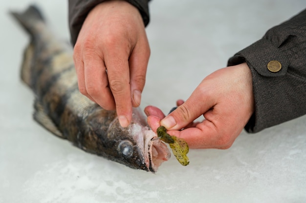 Kostenloses Foto mann, der den fisch vom köder der rute befreit