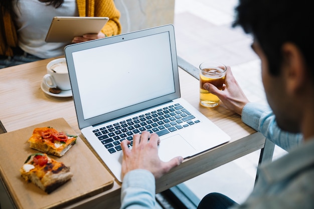 Mann, der den Laptop sitzt mit Getränk verwendet