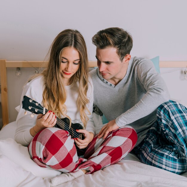 Mann, der die Frau spielt Ukulele betrachtet