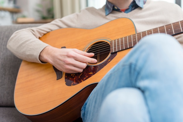 Kostenloses Foto mann, der die gitarre drinnen spielt