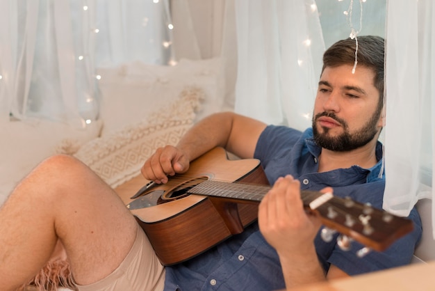 Kostenloses Foto mann, der die gitarre in einem wohnwagen spielt