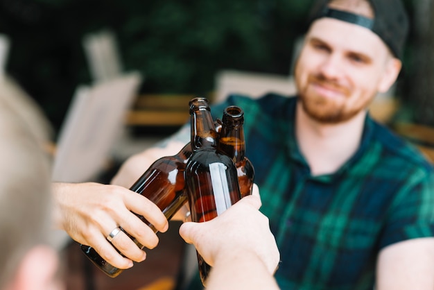 Mann, der die Glasflaschen Bier mit Freunden klirrt