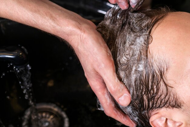 Mann, der die Haare eines Kunden wäscht