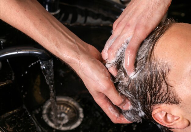 Mann, der die Haare eines Kunden wäscht