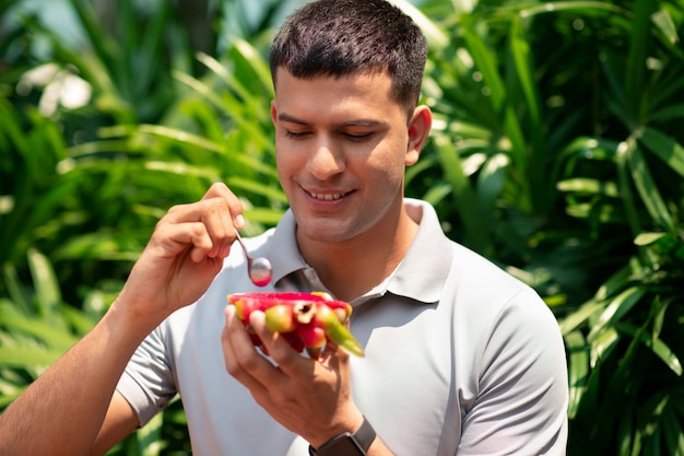 Mann, der Drachefrucht draußen isst