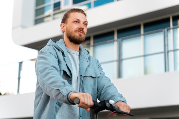 Mann, der draußen einen umweltfreundlichen Roller fährt