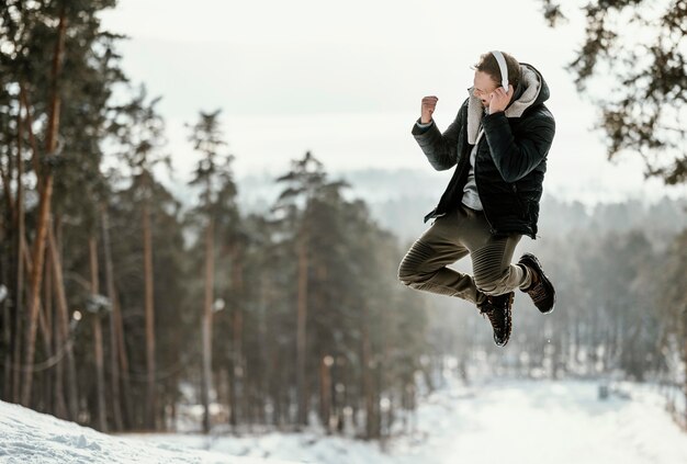 Mann, der draußen in der Natur während des Winters mit Kopienraum springt