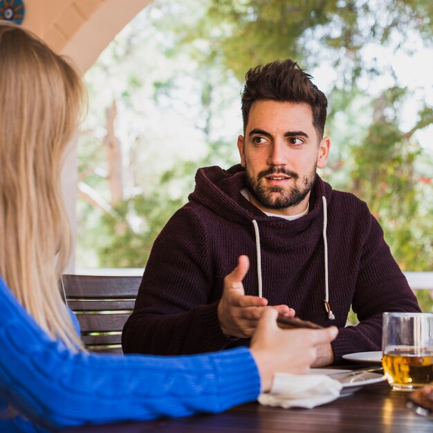 Mann, der draußen mit Frau bei Tisch spricht