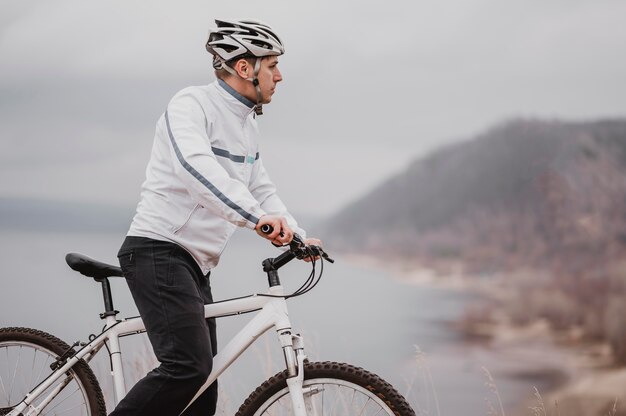 Mann, der ein Fahrrad an einem kalten Tag reitet und mit Kopierraum wegschaut