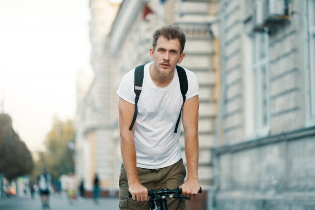 Mann, der ein Fahrrad in einer alten europäischen Stadt im Freien fährt