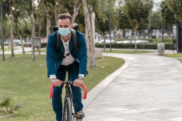 Mann, der ein Fahrrad reitet, während er eine medizinische Maske trägt