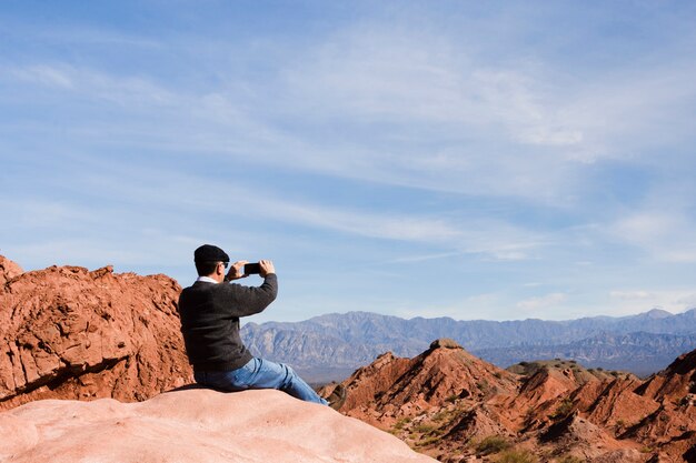 Mann, der ein Foto an der Berglandschaft macht