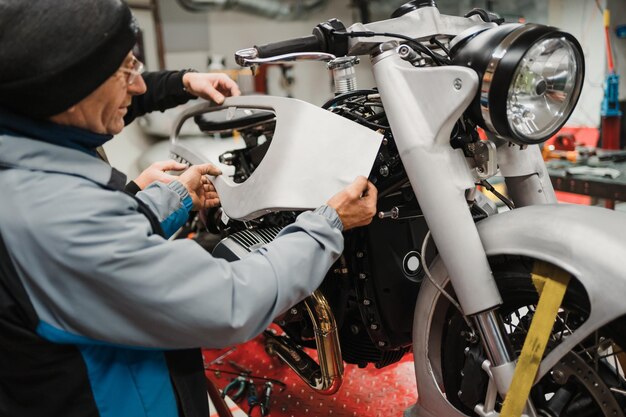 Mann, der ein Motorrad in einer modernen Werkstatt repariert