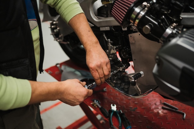 Mann, der ein Motorrad in einer modernen Werkstatt repariert