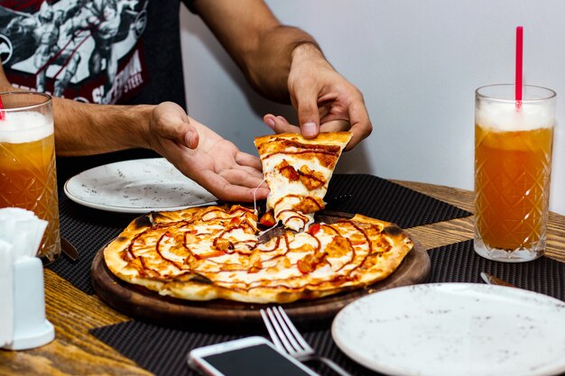 Kostenloses Foto mann, der ein stück hühnerpizza nimmt