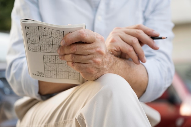 Kostenloses Foto mann, der ein sudoku-spiel auf papier genießt