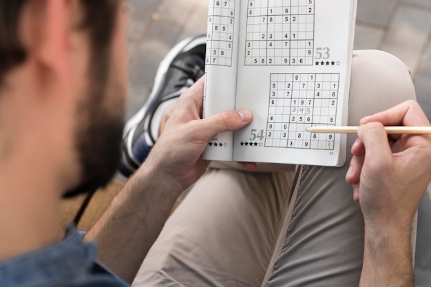 Kostenloses Foto mann, der ein sudoku-spiel auf papier genießt