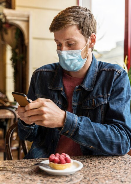 Mann, der eine Gesichtsmaske trägt, während er sein Telefon überprüft