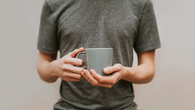 Mann, der eine graue keramische Kaffeetasse hält